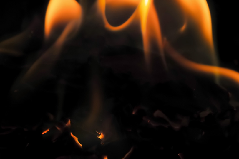 残り火の上で揺れる炎の写真画像