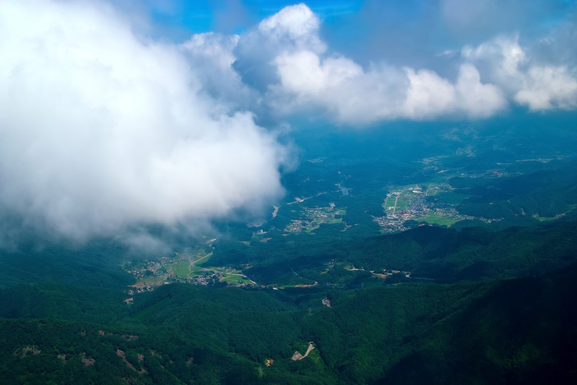 雲の下に見える山間の集落群の写真画像