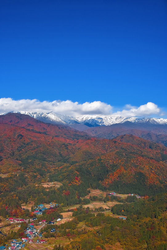 秋山の向こうの山脈に雪が積もるの写真画像
