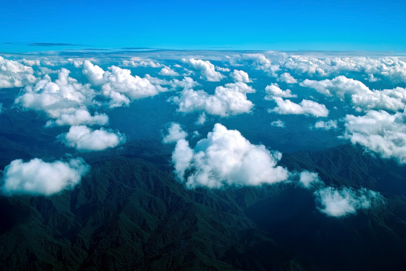 上空から見た果てしなく続く雲とそびえ立つ山々の写真画像