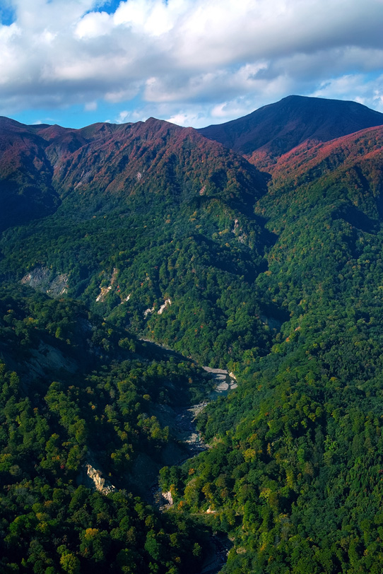 赤い山頂と緑の麓を流れる渓谷の写真画像