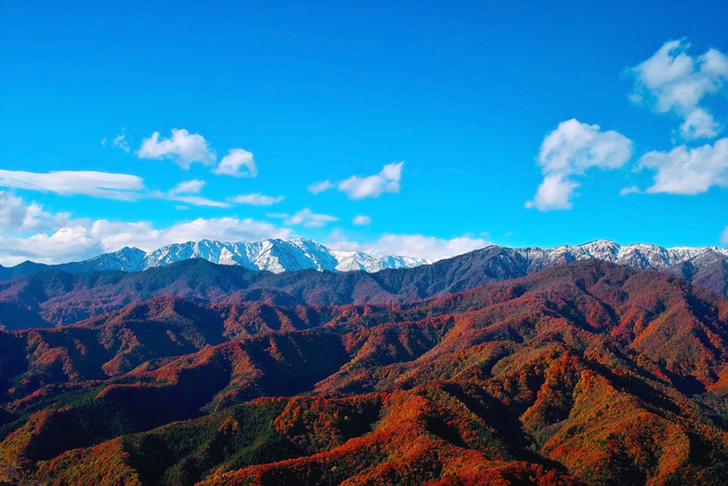 青空に映える紅葉の赤い山の写真画像