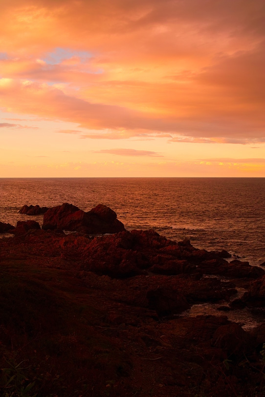 夕焼けの岩の多い海岸の写真画像