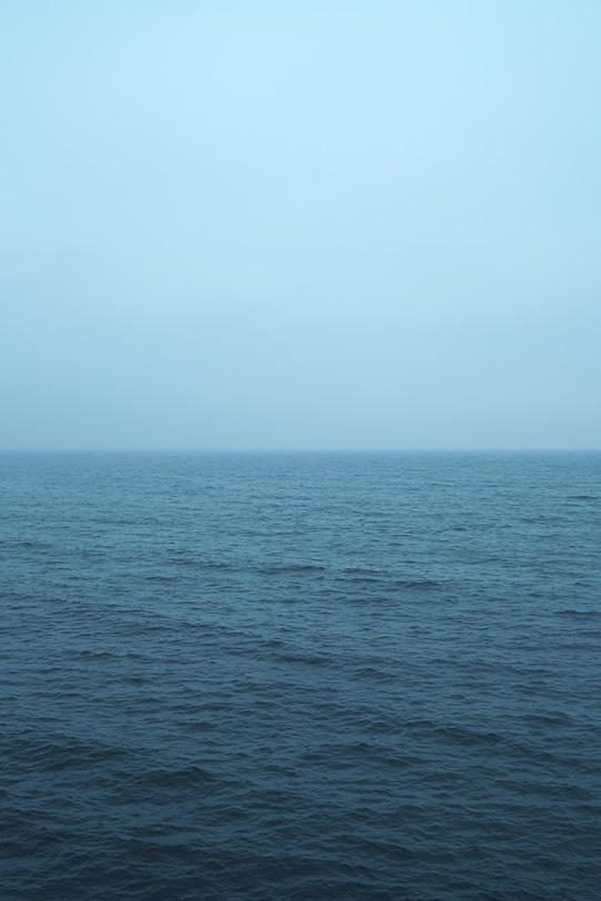 薄曇りの空と暗い海の写真画像