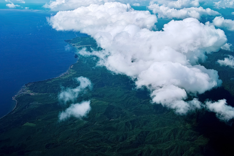 雲の下に見える海と陸の写真画像