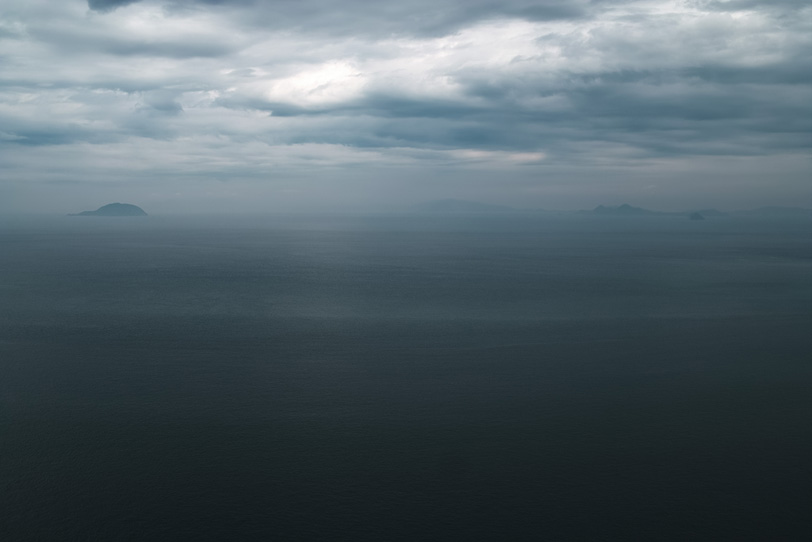暗い海に霞んで見える島の写真画像