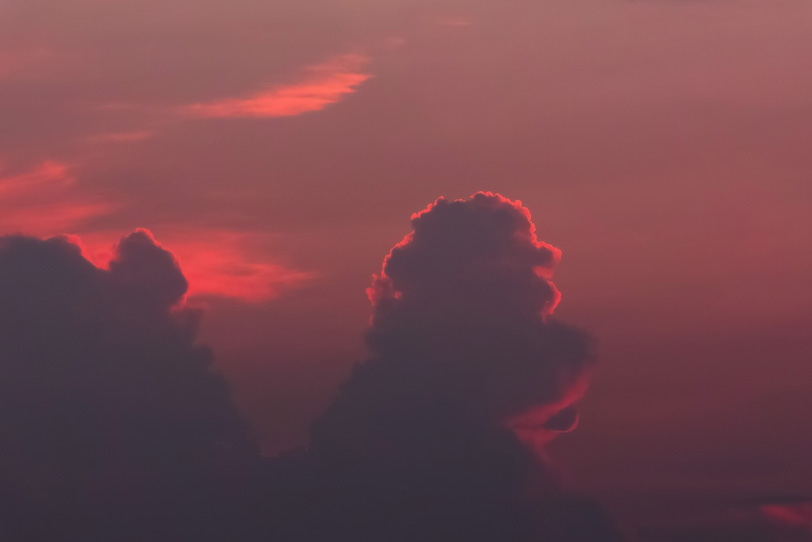 雲のシルエットを照らす夕焼けの光の写真画像