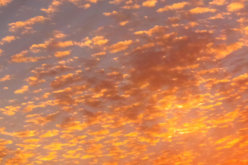 無数の雲が橙色に染まる夕焼けの写真画像