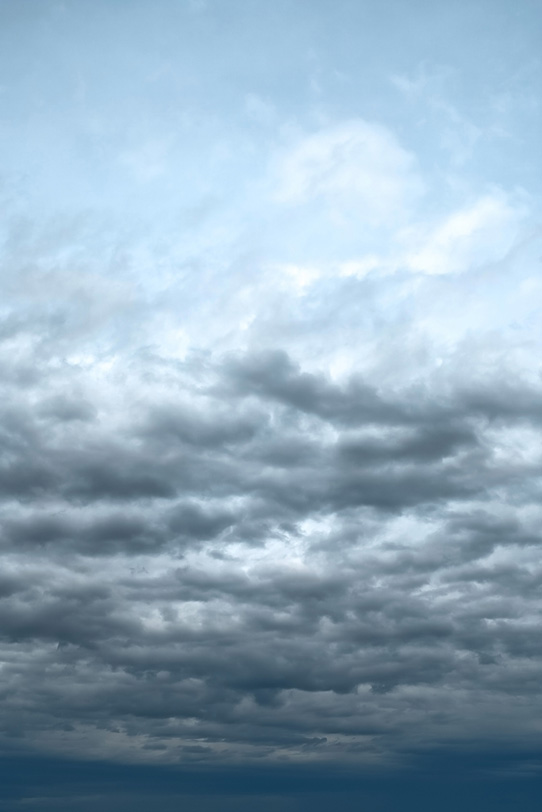 薄曇りの空に叢雲が押し寄せるの写真画像