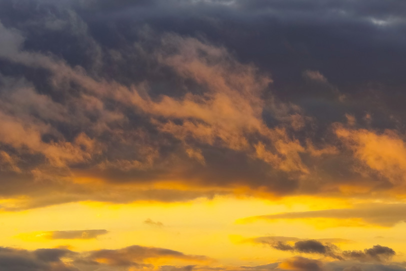 黄金色に輝く夕焼けと黒雲の空の写真画像