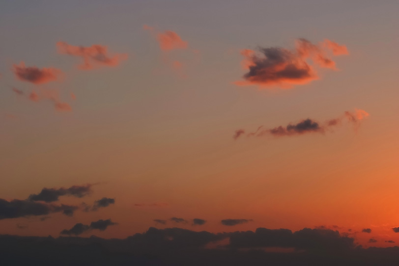 明澄な夕焼けに焦げた茜雲が漂うの写真画像