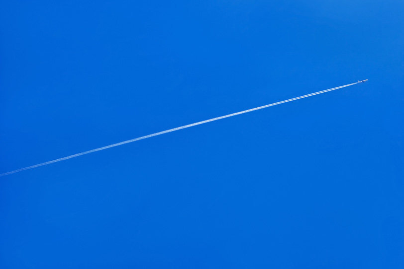 青空に一直線を描く飛行機雲の写真画像