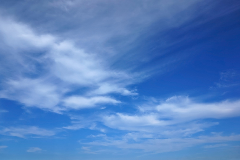 青空に筋を描きながら流れる雲の写真画像