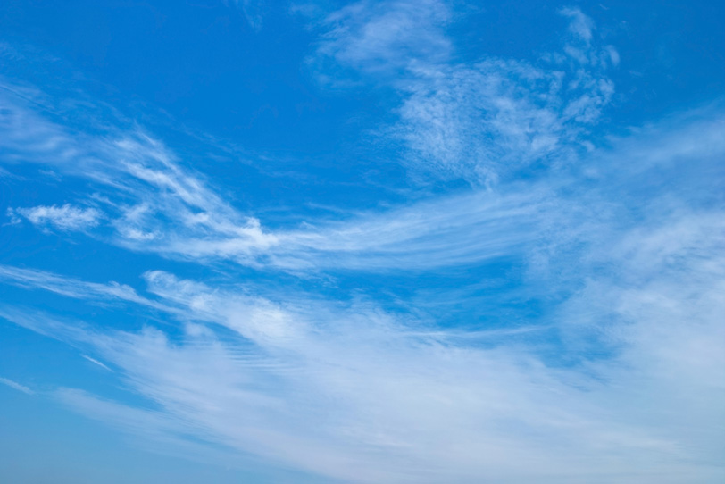 青空に尾を引いて流れる雲の写真画像