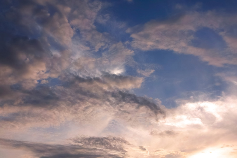 暗い青空を囲む夕焼けの雲の写真画像