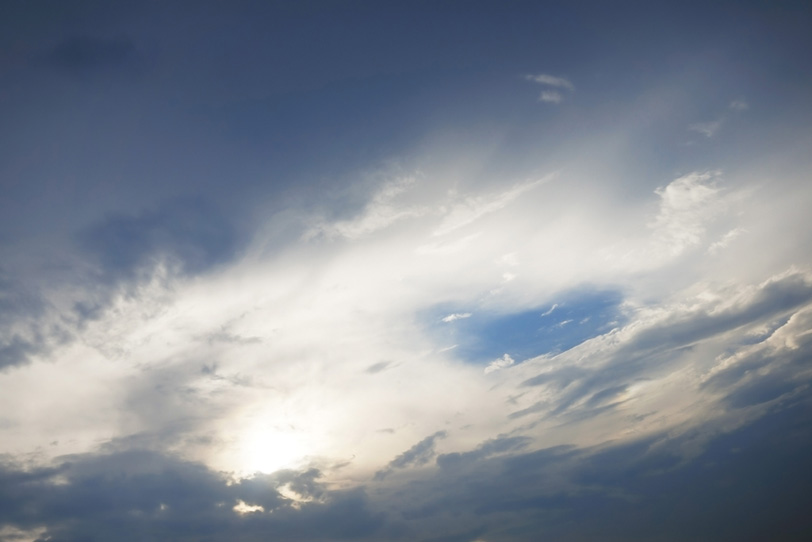 雲のベールに透ける太陽と青空の写真画像