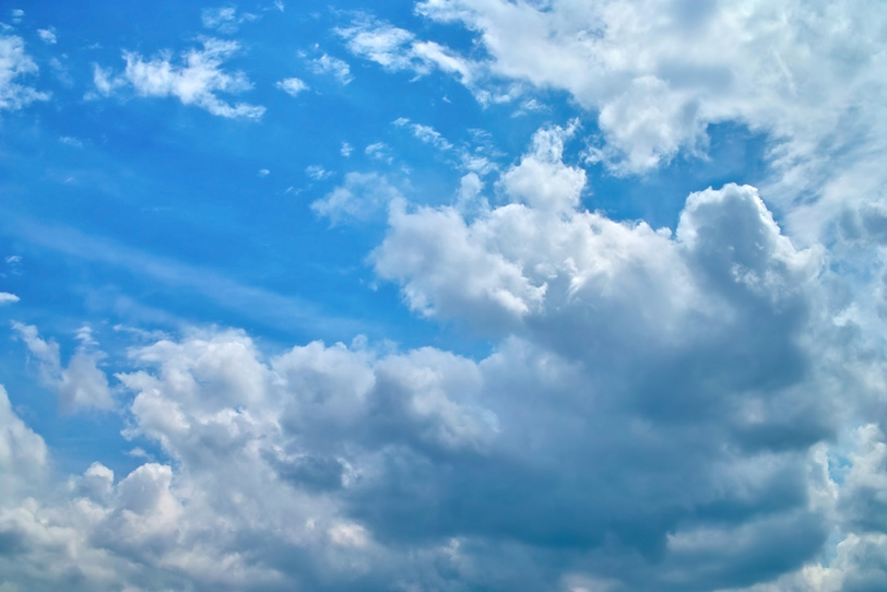 青空の下を覆い被さる様に進む雲の写真画像
