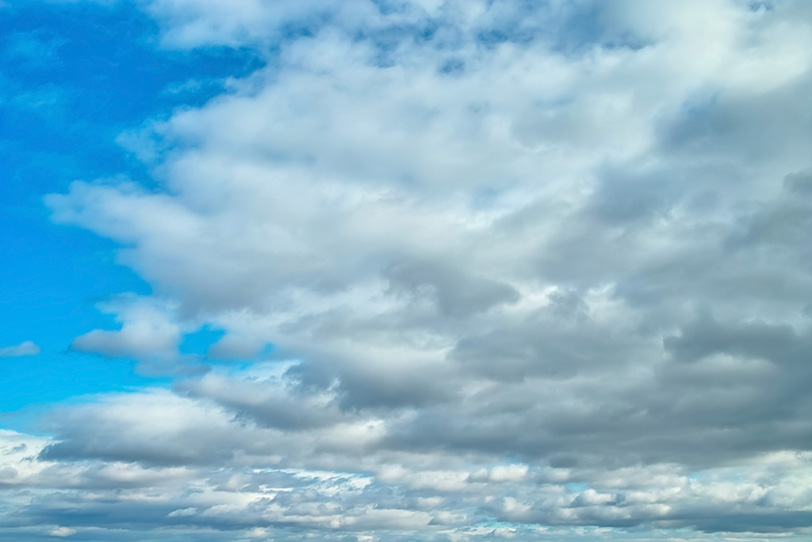 清澄な青空を覆い尽くそうとする雲の写真画像