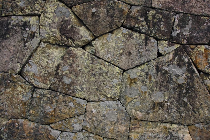 不規則な形の石を隙間なく積んだ壁の写真画像