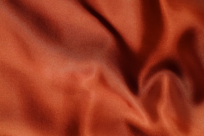 光沢のあるオレンジ色の布地の画像（布 ドレープの背景フリー画像）
