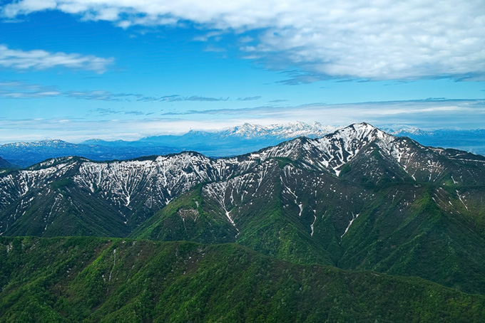 頂きにまだ雪を残す春の山の素材（背景 山 画像の背景フリー画像）