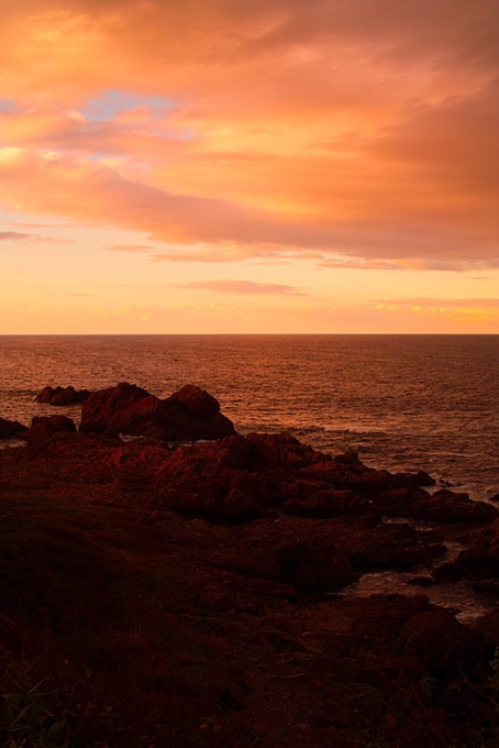 夕焼けの岩の多い海岸（夕景 写真の背景フリー画像）