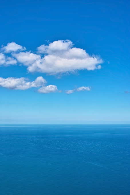 水平線に浮かぶ白い雲（海 風景の背景フリー画像）