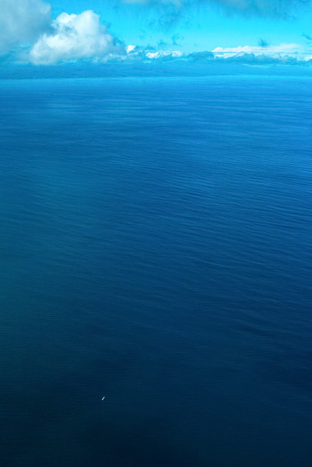 濃紺の海を漂う小さな船（海 写真の背景フリー画像）