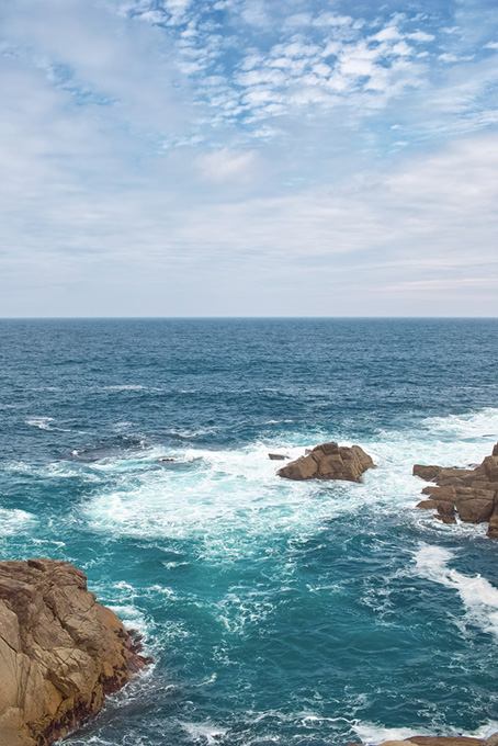 磯の岩場に砕ける波（海 風景の背景フリー画像）