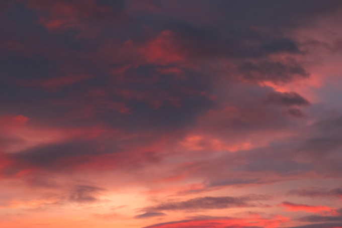 灰色の雲に反射する夕焼けの朱色の画像（背景 空 画像の背景フリー画像）