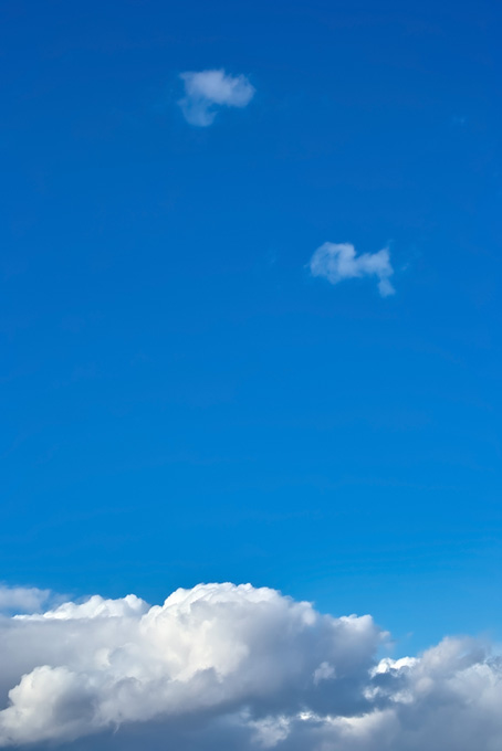 濃紺の青空が厚雲の上に広がる（空 テクスチャの背景フリー画像）