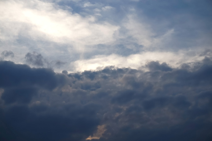 対峙する黒い乱層雲と輝く空（空 素材の背景フリー画像）